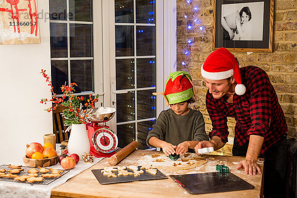 Mann und Sohn bereiten an der Küchentheke Weihnachtsplätzchen zu