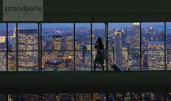 Silhouettierte Frau überquert nachts die Stadtbrücke über das Stadtbild von New York  USA