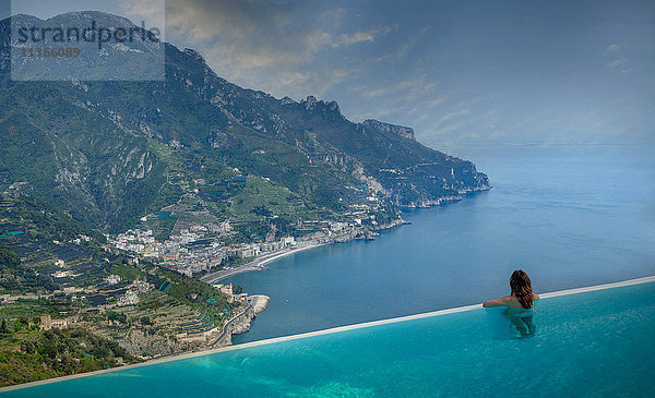 Rückansicht einer Frau  die vom Infinity-Pool auf die Küste schaut  Ravello  Amalfiküste  Italien