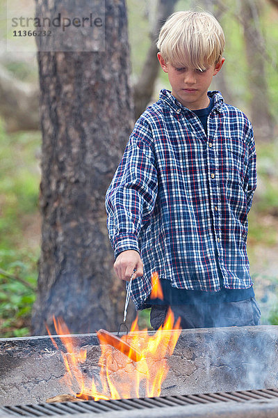 Junge beim Grillen von Wurst auf dem Flammengrill im Wald  Sedona  Arizona  USA