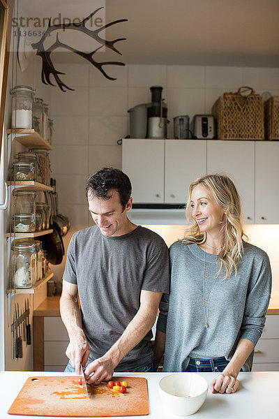 Mittleres erwachsenes Paar beim Schneiden von Kirschtomaten in der Küche