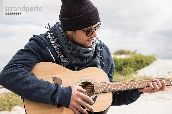 Junger Mann spielt akustische Gitarre am Strand  Western Cape  Südafrika