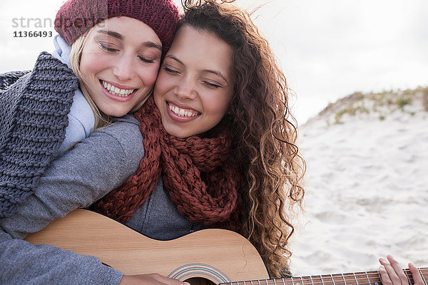 Porträt von zwei jungen Freundinnen beim Gitarrespielen am Strand  Western Cape  Südafrika