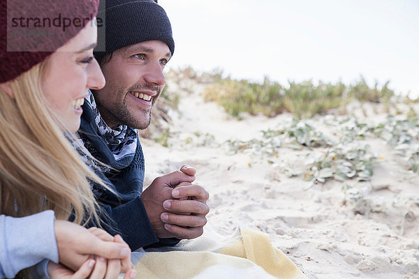 Junges Paar liegt auf einer Picknickdecke am Strand  Western Cape  Südafrika