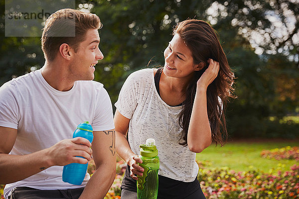 Mann und Frau trainieren im Park  plaudern während einer Wasserpause