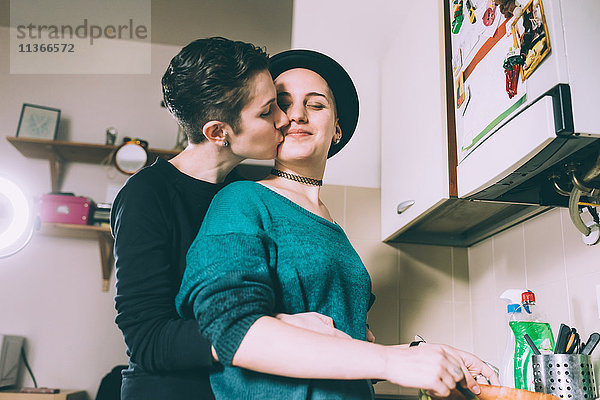 Junge Frau küsst Freundin in Küche