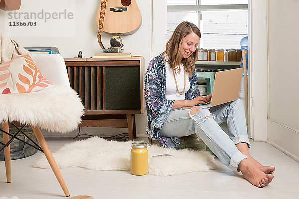 Frau sitzt mit Laptop im Wohnzimmer