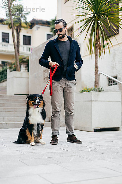 Mittelgroßer erwachsener Mann steht mit Haushund auf dem Stadtplatz