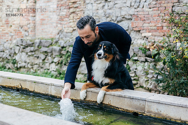Mittelgroßer erwachsener Mann mit Hunde-Spritzwassertrog