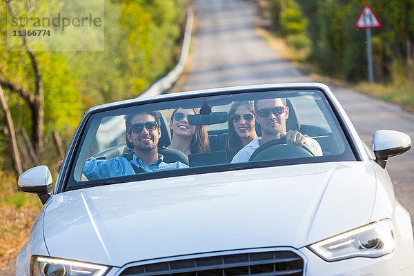 Vier erwachsene Freunde fahren auf einer Landstraße in einem Cabriolet  Mallorca  Spanien