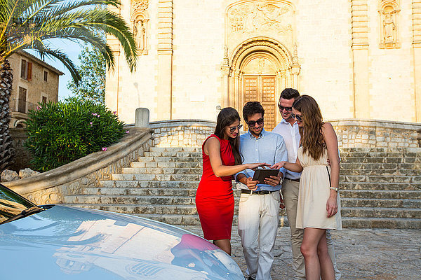 Zwei Touristenpaare schauen sich ein digitales Tablet in der Kirche an  Calvia  Mallorca  Spanien