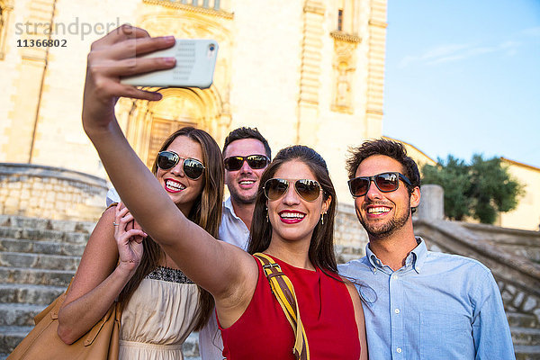 Zwei Touristenpaare mit Sonnenbrillen beim Selfie vor der Kirche  Calvia  Mallorca  Spanien
