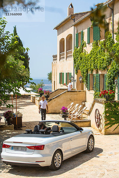 Pförtner empfängt Paar  das mit einem Cabrio zum Boutique-Hotel fährt  Mallorca  Spanien