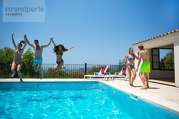 Junge Frauen und Männer springen gemeinsam in den Swimmingpool eines Boutique-Hotels  Mallorca  Spanien
