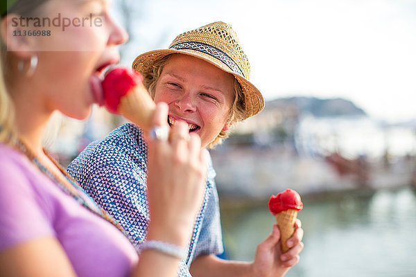 Junges Paar lacht und isst Eistüten am Wasser  Mallorca  Spanien