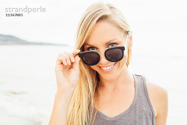 Porträt einer Frau mit Sonnenbrille  die lächelnd in die Kamera schaut