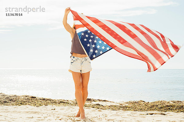 Frau mit erhobenen Strandarmen und amerikanischer Flagge