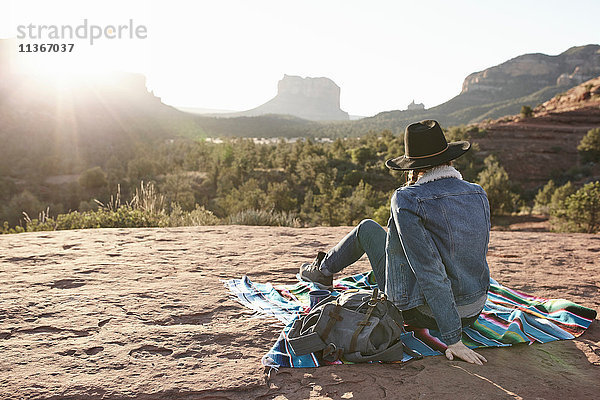 Frau sitzt auf einer Decke in der Wüste und schaut auf Ansicht  Rückansicht  Sedona  Arizona  USA