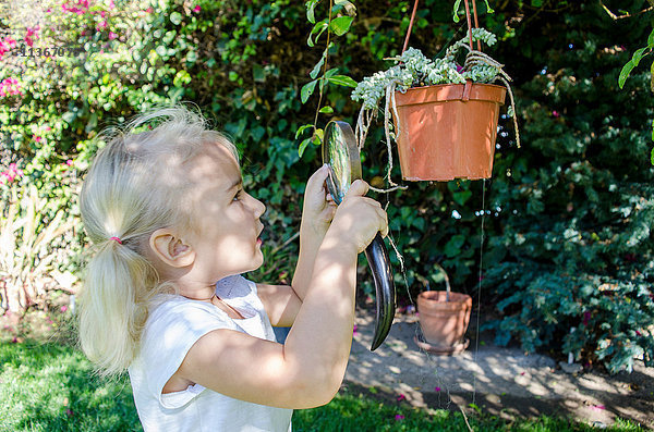 Junges Mädchen betrachtet Pflanzen durch eine Lupe