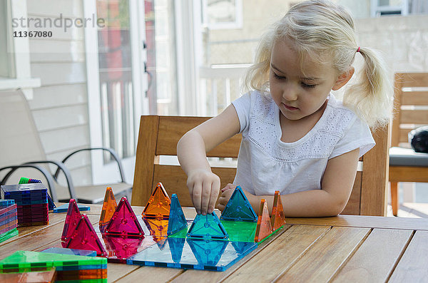 Junges Mädchen spielt mit dreieckigen Gebäudeformen