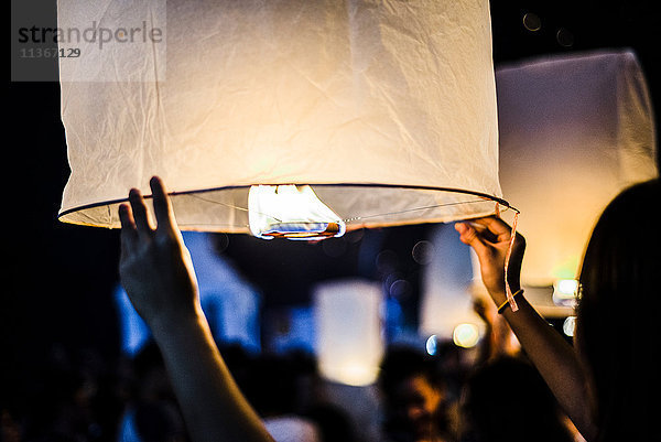 Junge Frau hält brennende Papierlaterne in der Hand und wartet auf ihre Freilassung beim Loy Krathong Paper Latern Festival in Chiang Mai  Thailand