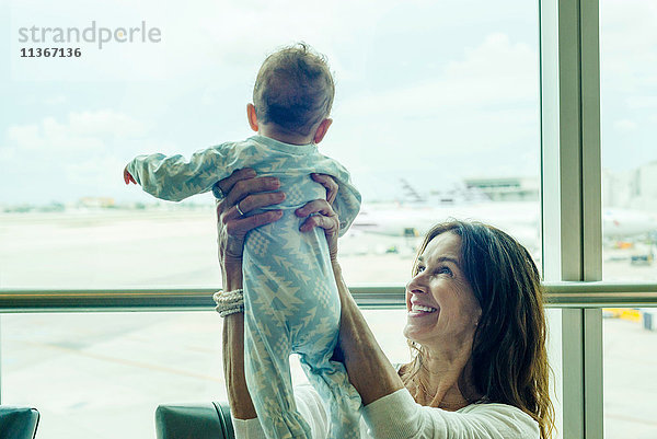 Großmutter hebt Baby in der Luft am Flughafen