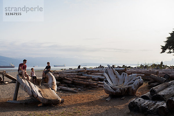 Familie sitzt auf Holzskulptur am Strand  Vancouver  Britisch-Kolumbien  Kanada