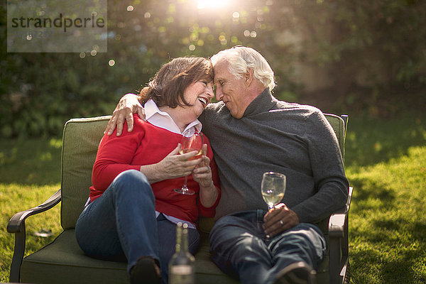 Romantisches Seniorenpaar sitzt von Angesicht zu Angesicht auf dem Sofa im Garten