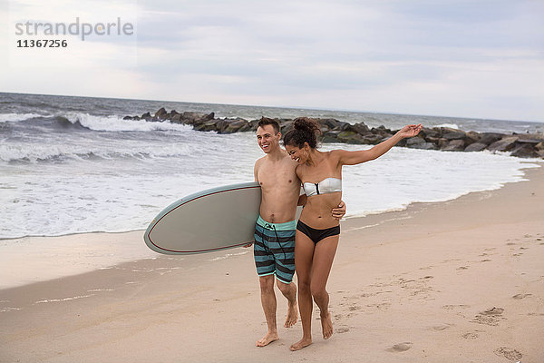 Romantisches junges Surferpaar beim Spaziergang am Rockaway Beach  New York State  USA