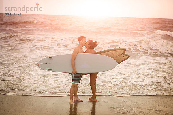 Romantisches junges Surferpaar küsst sich am Rockaway Beach  New York State  USA