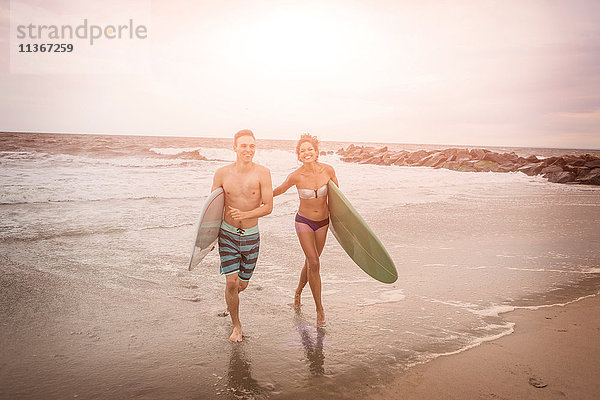 Junges Surferpaar mit Surfbrettern am Rockaway Beach  New York State  USA