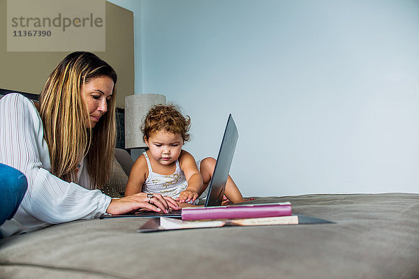 Mutter benutzt Laptop im Bett mit Tochter