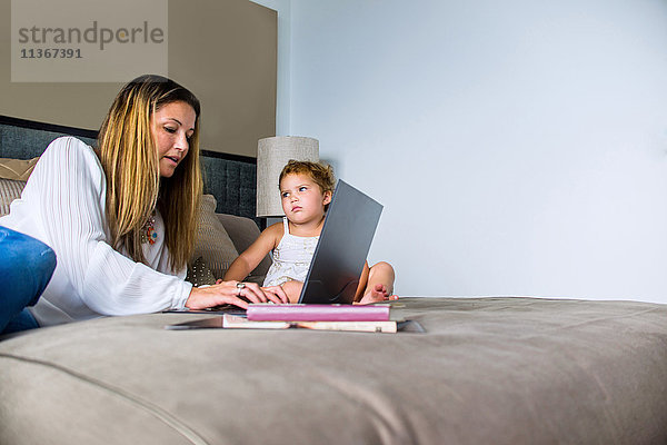 Mutter benutzt Laptop im Bett mit Tochter