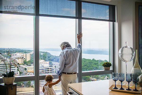 Großvater hält die Hand der Enkelin und schaut aus dem Fenster.