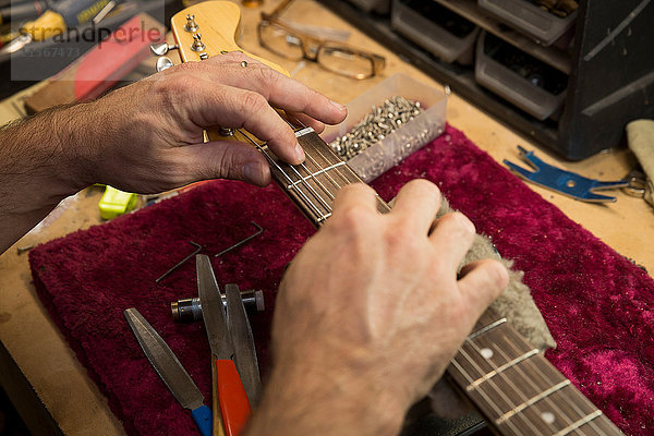 Beschnittene Ansicht der Hände des Gitarrenbauers bei der Herstellung der Gitarre