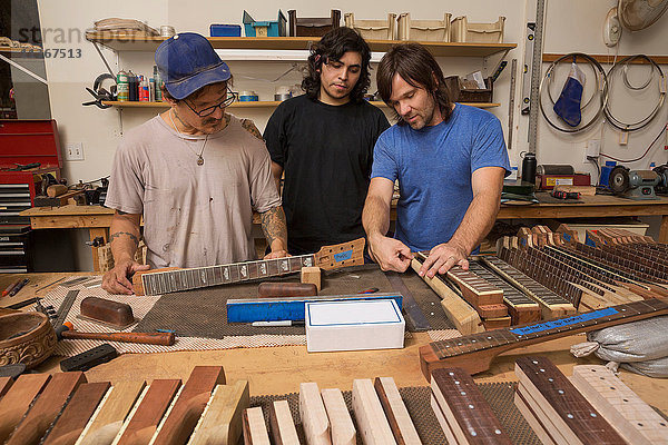 Gitarrenbauer in der Werkstatt bei der Qualitätsprüfung von Gitarrenhälsen