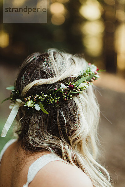 Rückansicht einer Frau mit Blumen im Haar  die wegschaut