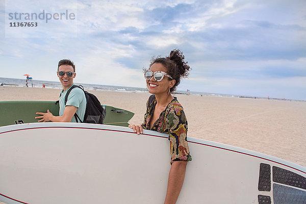 Junges Paar mit Surfbrettern am Rockaway Beach  New York State  USA