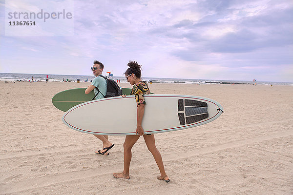Junges Paar mit Surfbrettern am Rockaway Beach  New York State  USA