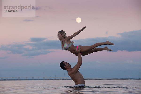 Mittelgroßer erwachsener Mann  der in der Abenddämmerung seine Freundin aus dem Meer aufhält  Santa Rosa Beach  Florida  USA
