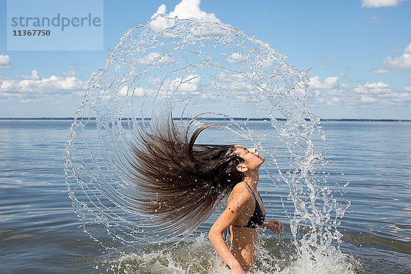 Junge Frau plätschert und wirft lange Haare vom Meer zurück  Santa Rosa Beach  Florida  USA