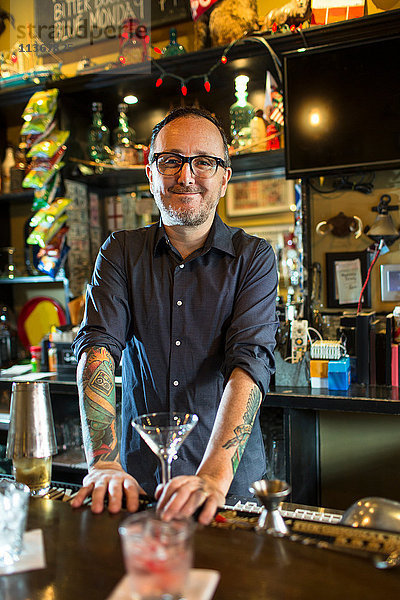 Porträt eines Barkeepers mit Cocktailglas am Tresen einer Gaststätte