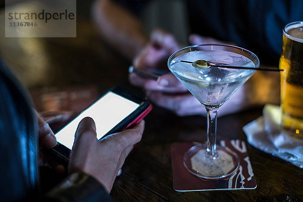 Nahaufnahme einer weiblichen Hand mit einem Smartphone in einer Gaststätte