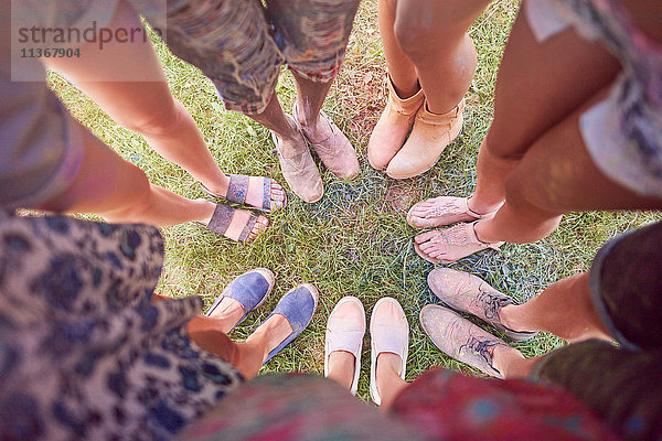 Gruppe von Freunden beim Fest  mit bunter Pulverfarbe überzogen  im Kreis stehend  erhöhte Ansicht der Füße