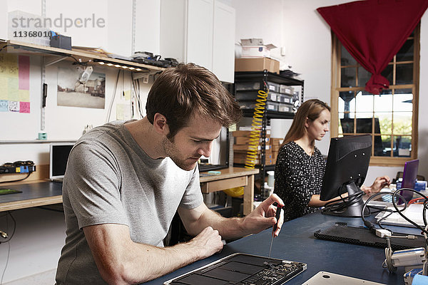 Ein junger Mann und eine junge Frau arbeiten an einer Werkbank in einem Technologielabor.