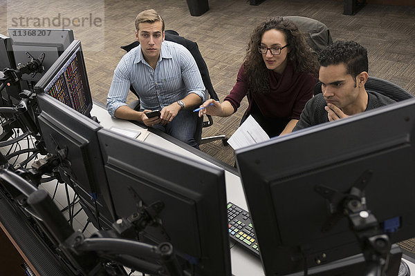 Junge Händler bei einem Treffen vor Computerbildschirmen
