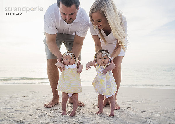 Glückliche Familie mit zwei kleinen Mädchen (2-5 Monate) am Strand