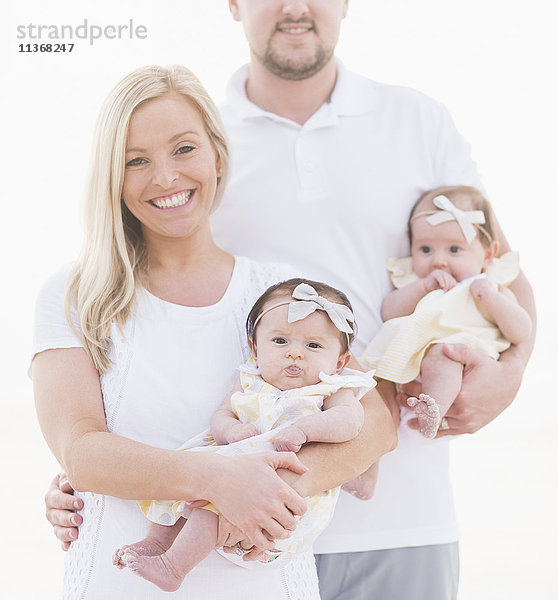 Studioaufnahme Porträt der glücklichen Familie mit zwei Baby-Mädchen (2-5 Monate) auf weißem Hintergrund