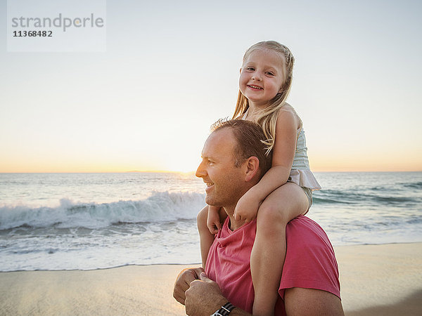 Vater trägt Tochter (4-5) am Strand