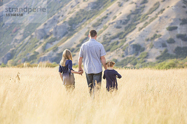 Vater mit zwei Töchtern (4-5  8-9) beim Spaziergang auf einem Feld